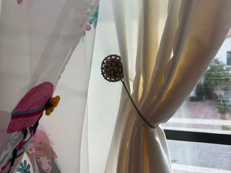 Decorative magnetic tieback for eyelet curtains